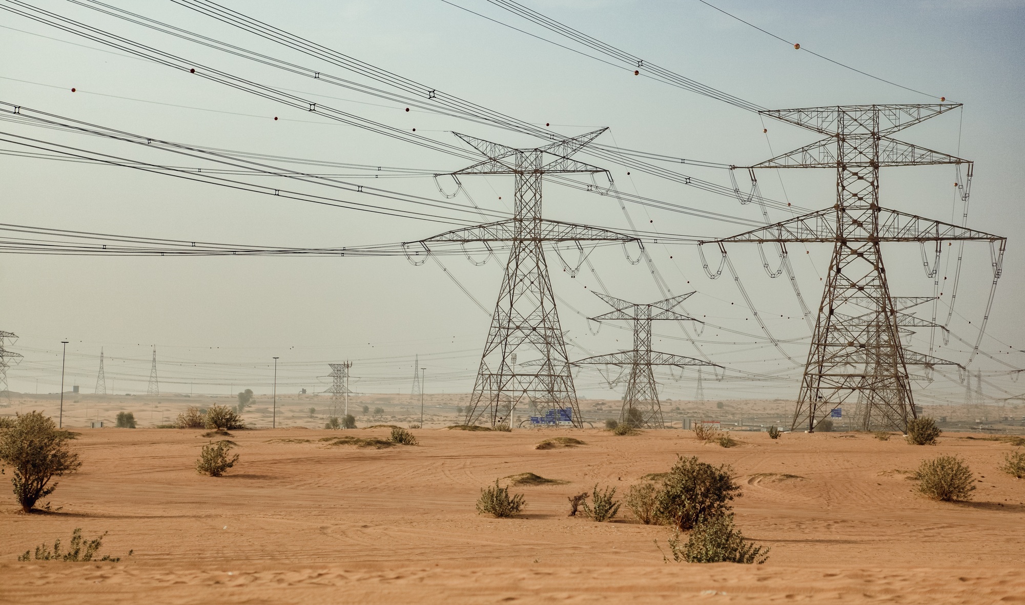 Power lines stretch across the sandy desert landscape of Dubai UAE
